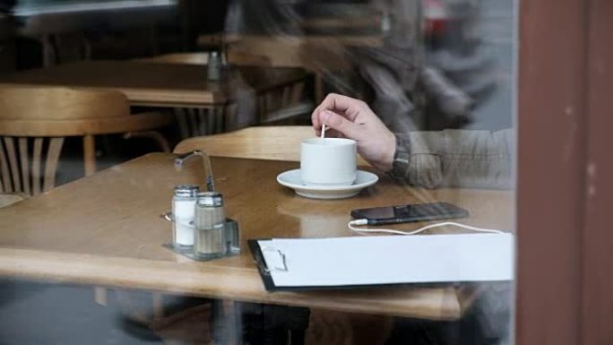 在咖啡馆里，商人的手拿着咖啡勺的特写