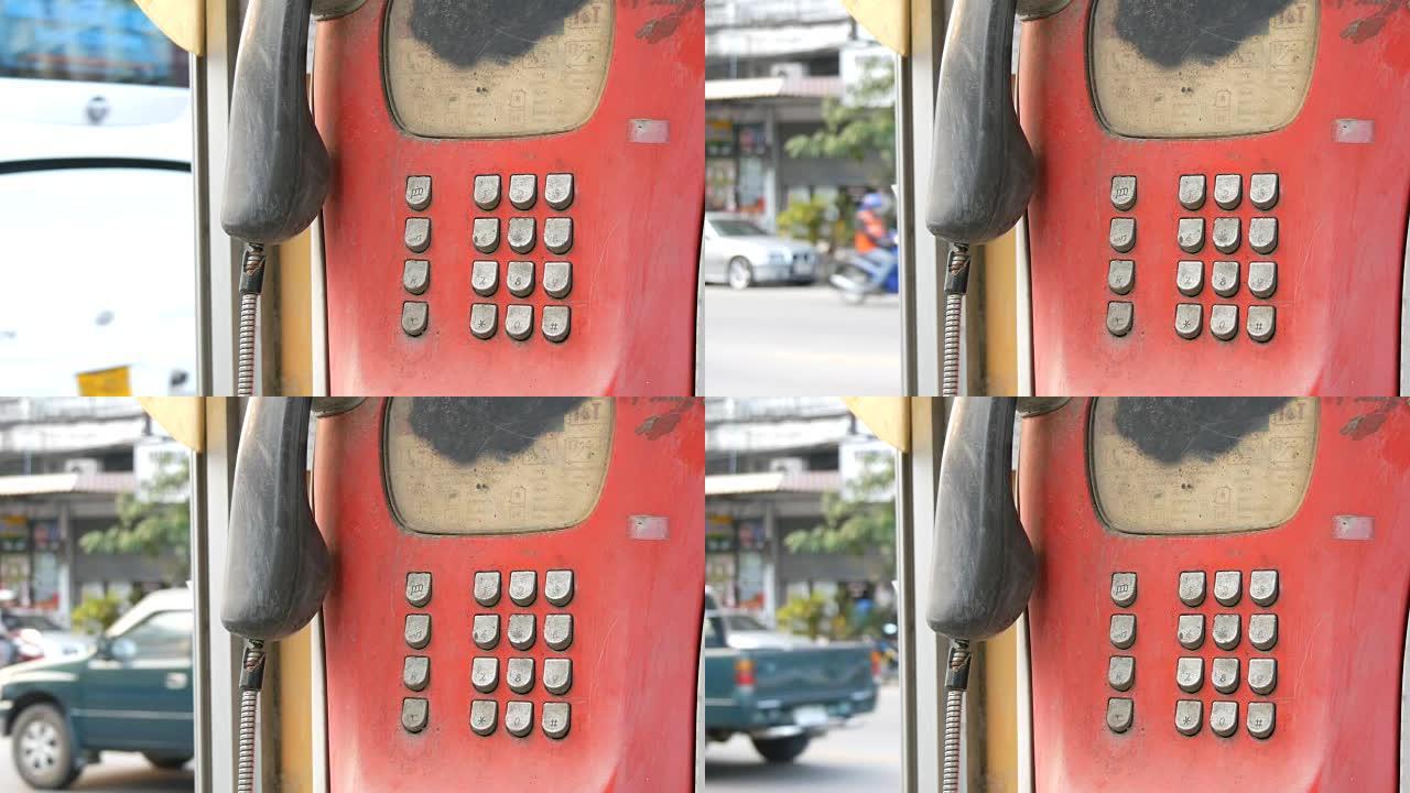 城市街道上破旧的红色电话机。电话亭里的老式电话