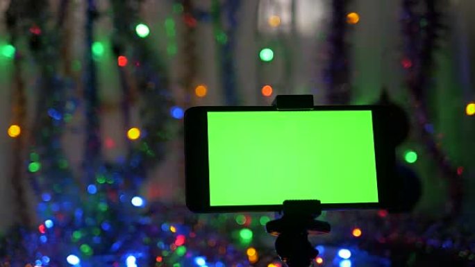 带有绿色屏幕的智能手机，在新年背景上。摄像机在物体周围的运动。