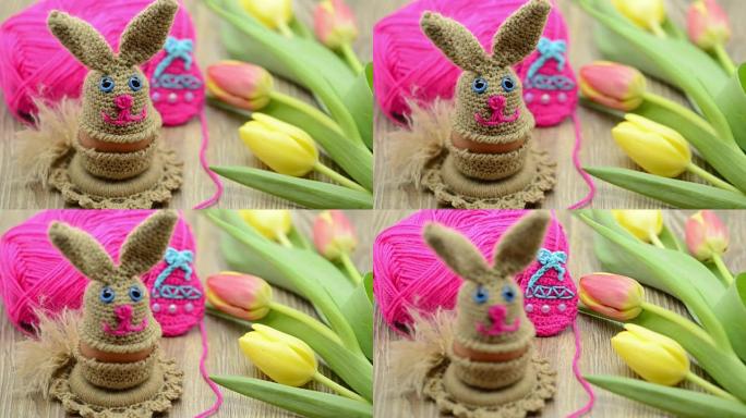 羊毛钩针复活节兔子蛋杯。背景为新鲜郁金香和羊毛球