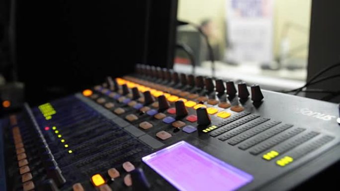 在直播电视转播期间，专业音频操作员在音频混合器旋钮上工作。