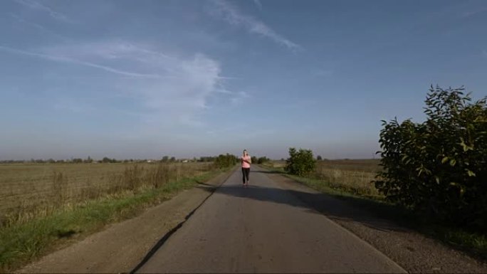 日落时在乡村道路上奔跑的年轻女子的鸟瞰图。
