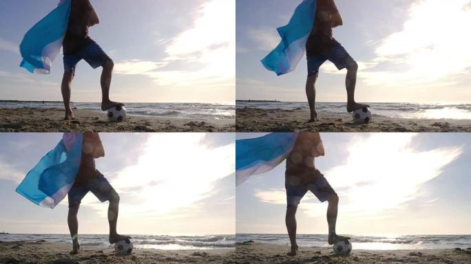 戴着阿根廷国旗的年轻人作为超级英雄斗篷，脚踩着足球站在海边的沙滩上，日落时看着海滩上的海洋摄像机st