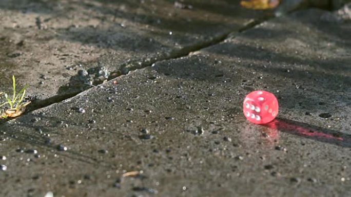 红色骰子以慢动作落在混凝土板上