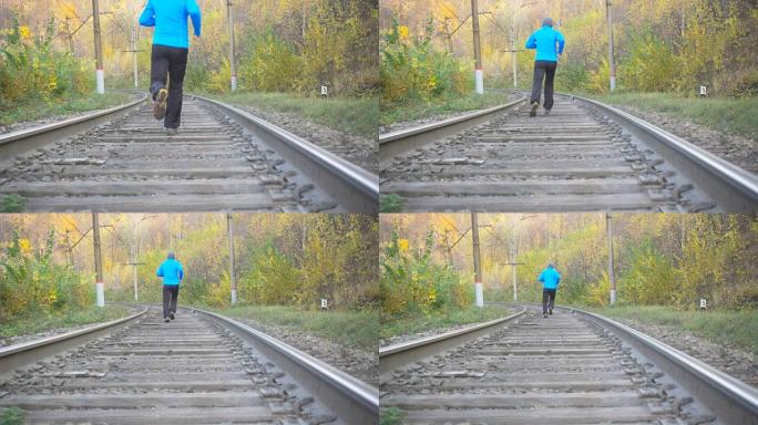 男子慢跑火车在秋天的森林里追踪铁路。在鼓舞人心的秋季景观中越野跑步时，在户外训练和锻炼。运动动机。慢