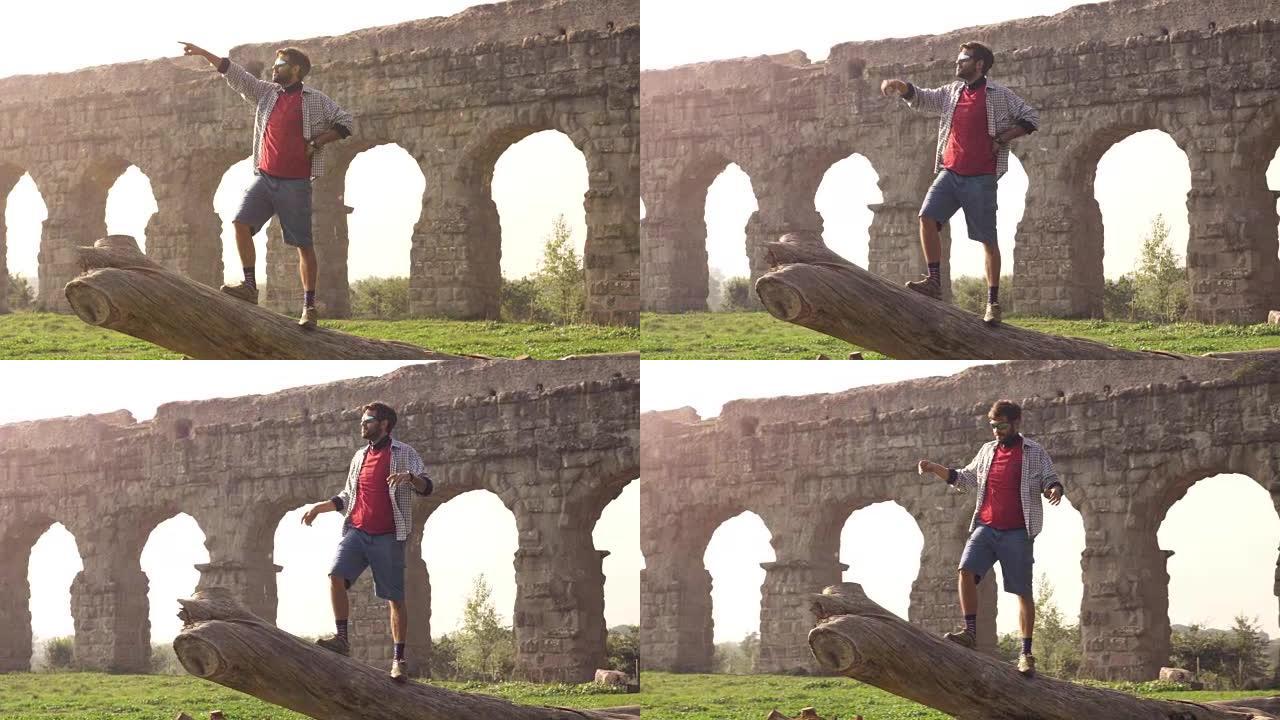 年轻的冒险家游客站在原木树干的顶部，在罗马parco degli acquedotti公园的古罗马渡
