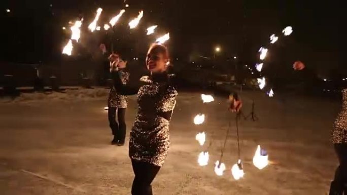 令人惊叹的部落火灾表演在冬天的夜晚在飘雪下跳舞。舞蹈团在下雪的天气用火炬灯和烟火表演