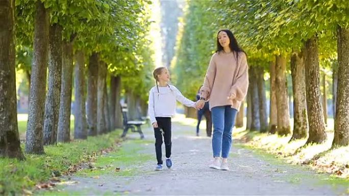 秋天的家庭。年轻的母亲和小孩散步在秋天的公园里享受温暖的一天