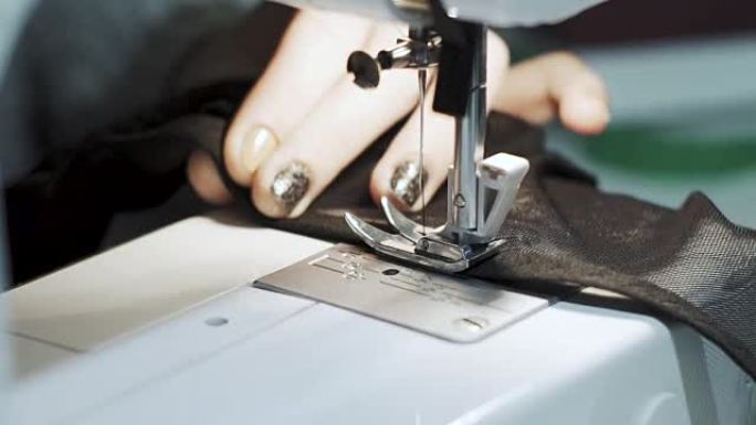 在缝纫机上工作的女性手的特写镜头。年轻女性概念设计师在家里做缝纫机。时尚和剪裁。慢动作