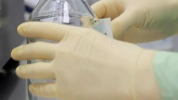 实验室工作人员用透明液体在瓶子上粘贴贴纸
