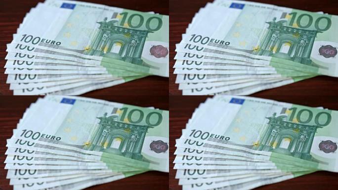 在桌子上散布成堆的一百欧元钞票