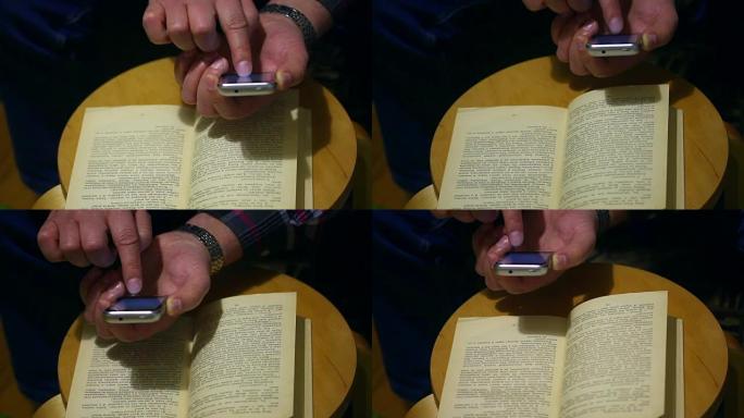 一个退休年龄的人在一本纸质书的智能手机页面上拍照。打开的书放在椅子上。这个人翻过一页。