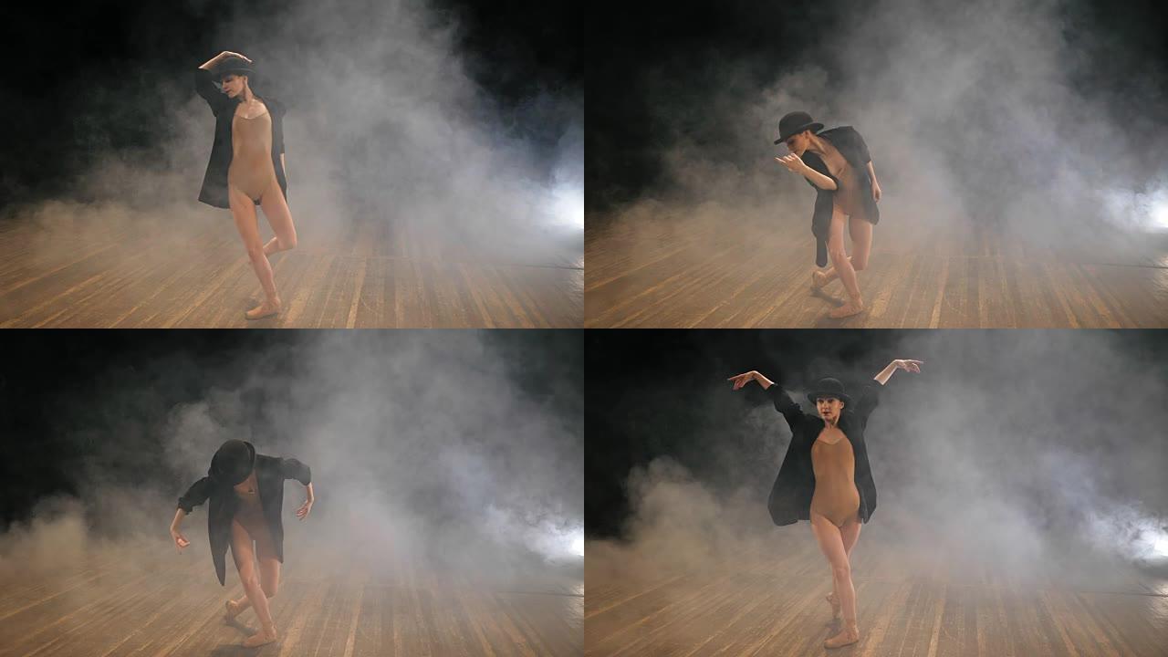 穿着黑色长夹克性感紧身衣的芭蕾舞女演员在舞台上舞动着神奇的灯光和烟雾，慢动作。年轻迷人的舞者穿着芭蕾