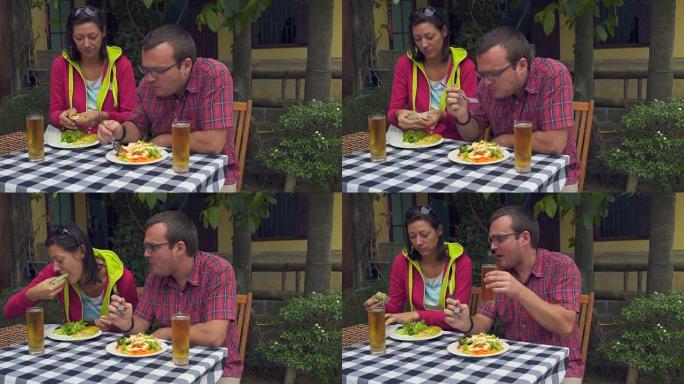 女人和男人坐在街上的一家餐馆里吃素食和喝啤酒