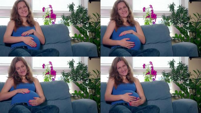微笑的孕妇看着相机抚摸她的肚子