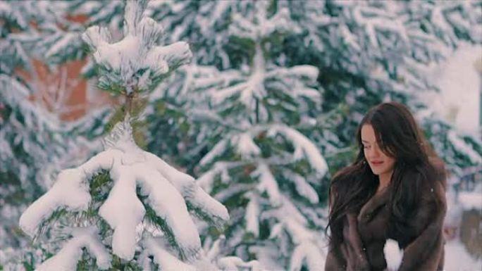 黑发女人在寒假慢动作中向空中扔雪