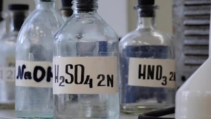 实验室储存在架子上的溶液瓶。装有NaOH，H2so4和hno3化学溶液的瓶子。硫酸、氢氧化钠、硝酸