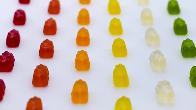 五颜六色的小熊软糖，甜美的水果果冻糖果行在白色背景上垂直移动