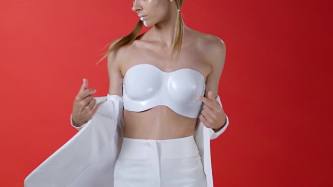 穿着白色夹克的时装模特展示塑料胸罩。时尚视频。