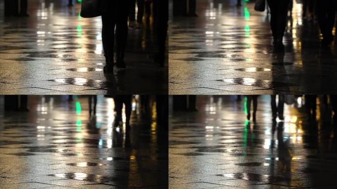 路灯潮湿路面上无法辨认的人的倒影。长长的阴影。下雨的夜晚在城市街道上，有路灯，雨水中有闪亮的沥青。无