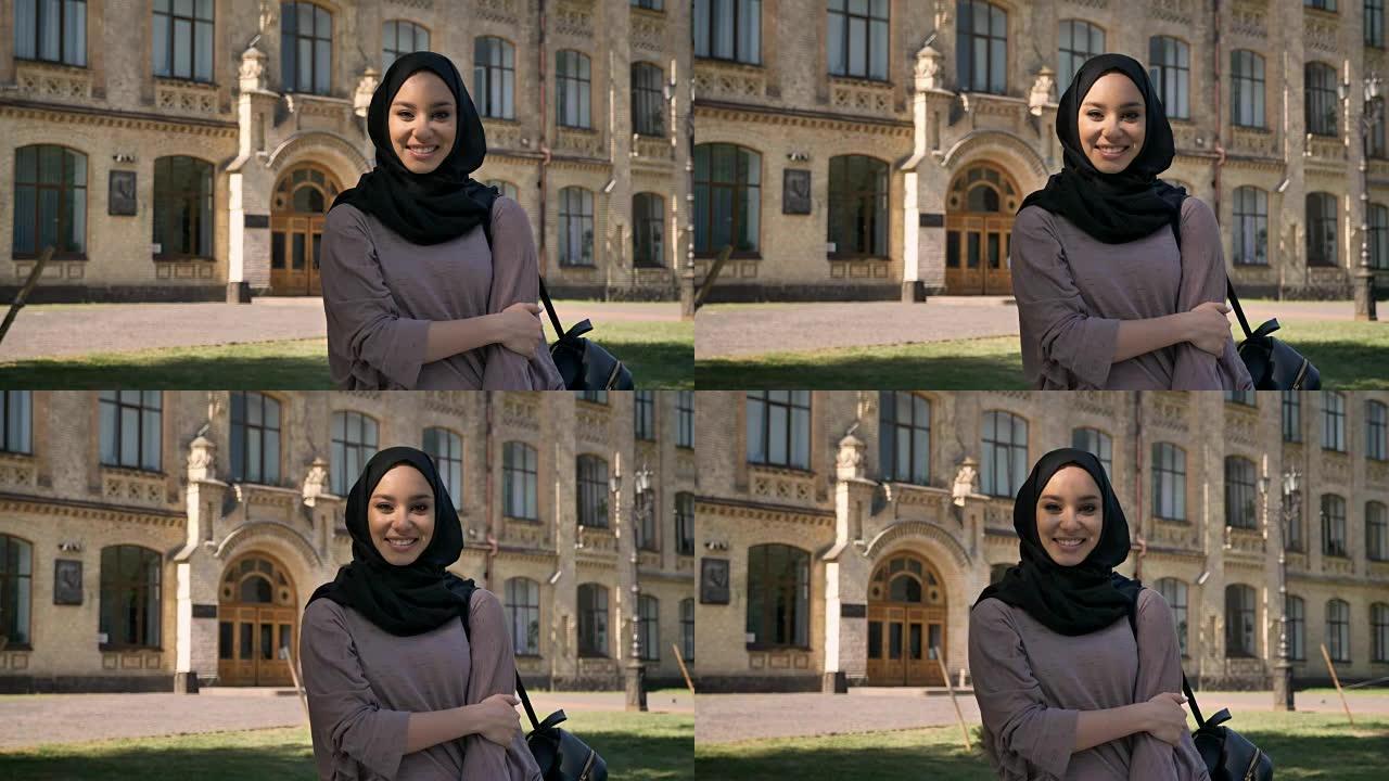 戴着头巾的年轻甜美穆斯林女孩在夏天的白天站着微笑，看着镜头，建立在背景和宗教概念上