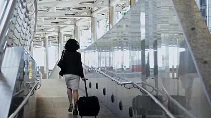 年轻的女商人匆忙拖着行李走