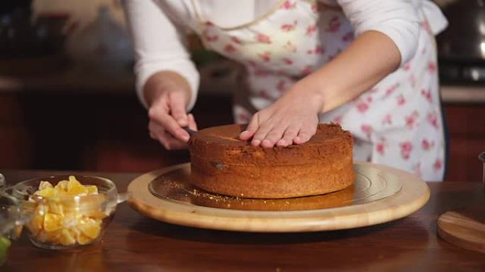 一个女人的手的特写镜头将新鲜出炉的蛋糕切成碎片