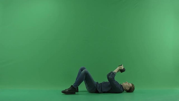 摄影师躺在背后在绿色屏幕上拍照