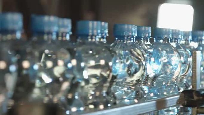 装满的蓝盖水瓶在工厂生产线上缓慢移动