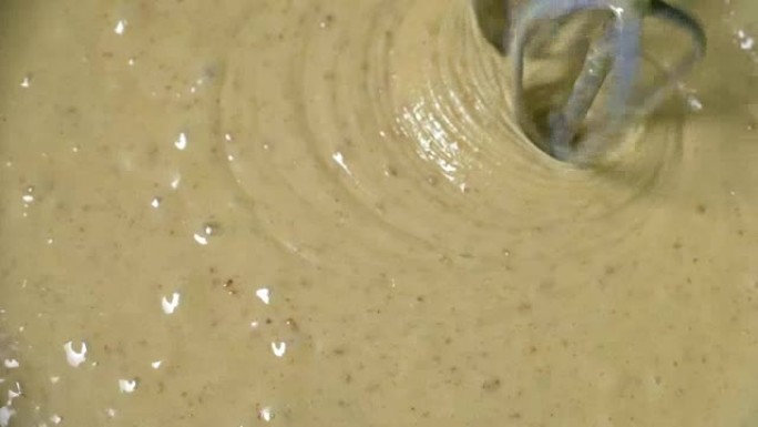 用搅拌器混合面团。用搅拌器烹饪奶油面团，以180fps的速度慢动作拍摄。浓稠液体上美丽的波浪。纸杯蛋