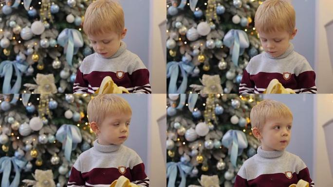 一个小孩在圣诞树附近吃香蕉。
