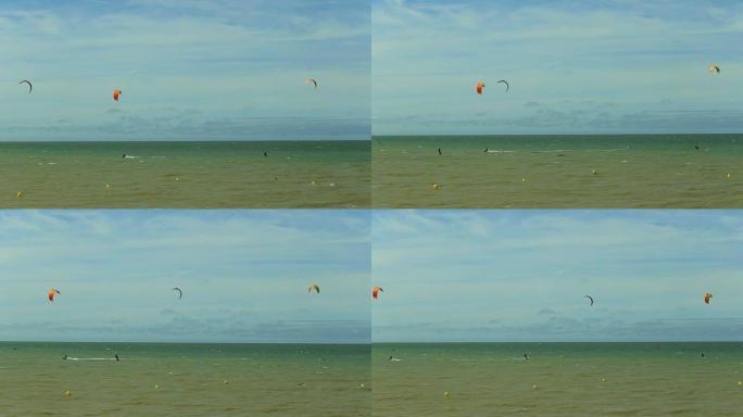 Kiters riding in waves in the summertime, Normandy