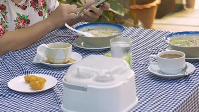 女人在吃早餐时玩智能手机