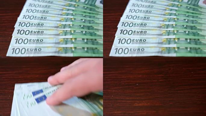 在桌子上散布成堆的一百欧元钞票