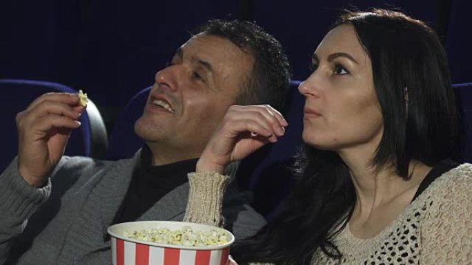 一对成熟的夫妇在电影院一起看电影的特写