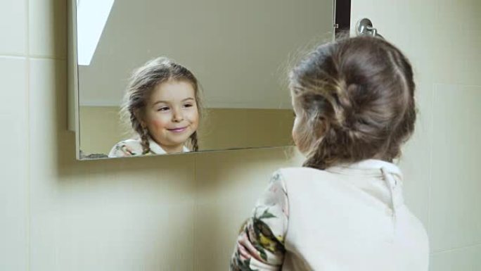 可爱的小女孩在镜子前用刷子在脸上涂抹粉末