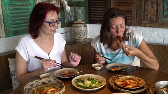 餐厅里的妇女吃海鲜和鸡肉串