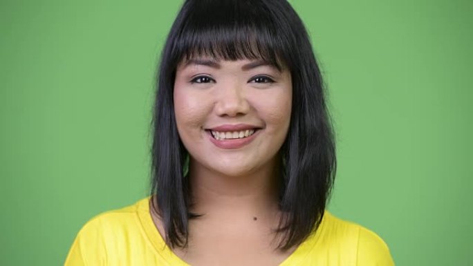 美丽快乐的亚洲女人在绿色背景下微笑
