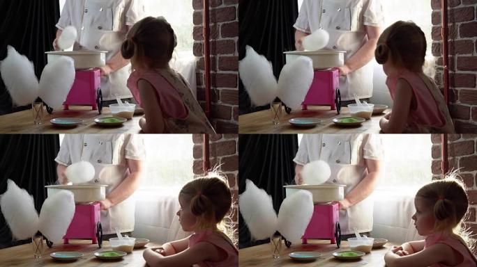 一个男厨师在一个可爱的小女孩的专用机器上制作棉花糖。