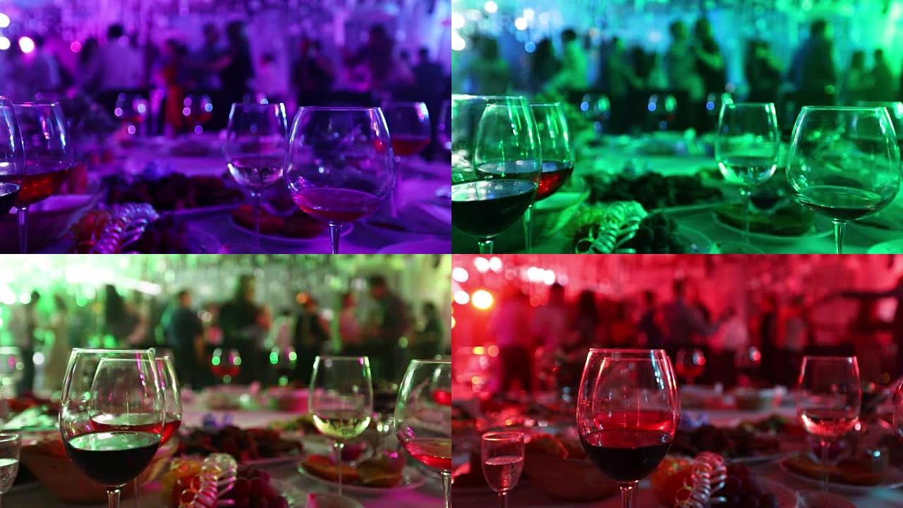 在餐厅或夜总会举行的青年聚会，在跳舞的人的剪影，舞台灯光和紫色填充，浅景深的背景下摆满酒精和食物的宴
