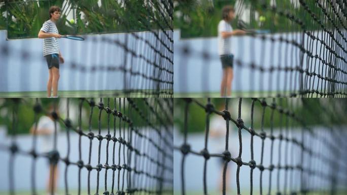 通过英俊男子的模糊网格观看用球拍打网球。在慢动作中改变焦点以啮合。1920x1080