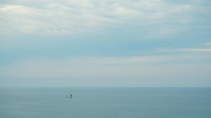 一艘红色帆在海里的帆船。