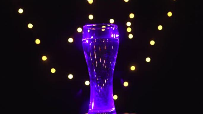 紫外线中的一杯水在旋转。紫外线鸡尾酒。酒吧概念