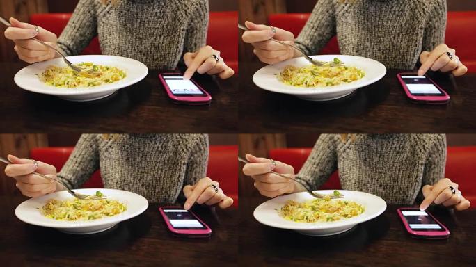 漂亮的年轻女孩在咖啡馆吃泰国米饭和蔬菜。一名妇女在餐厅的晚餐中使用智能手机