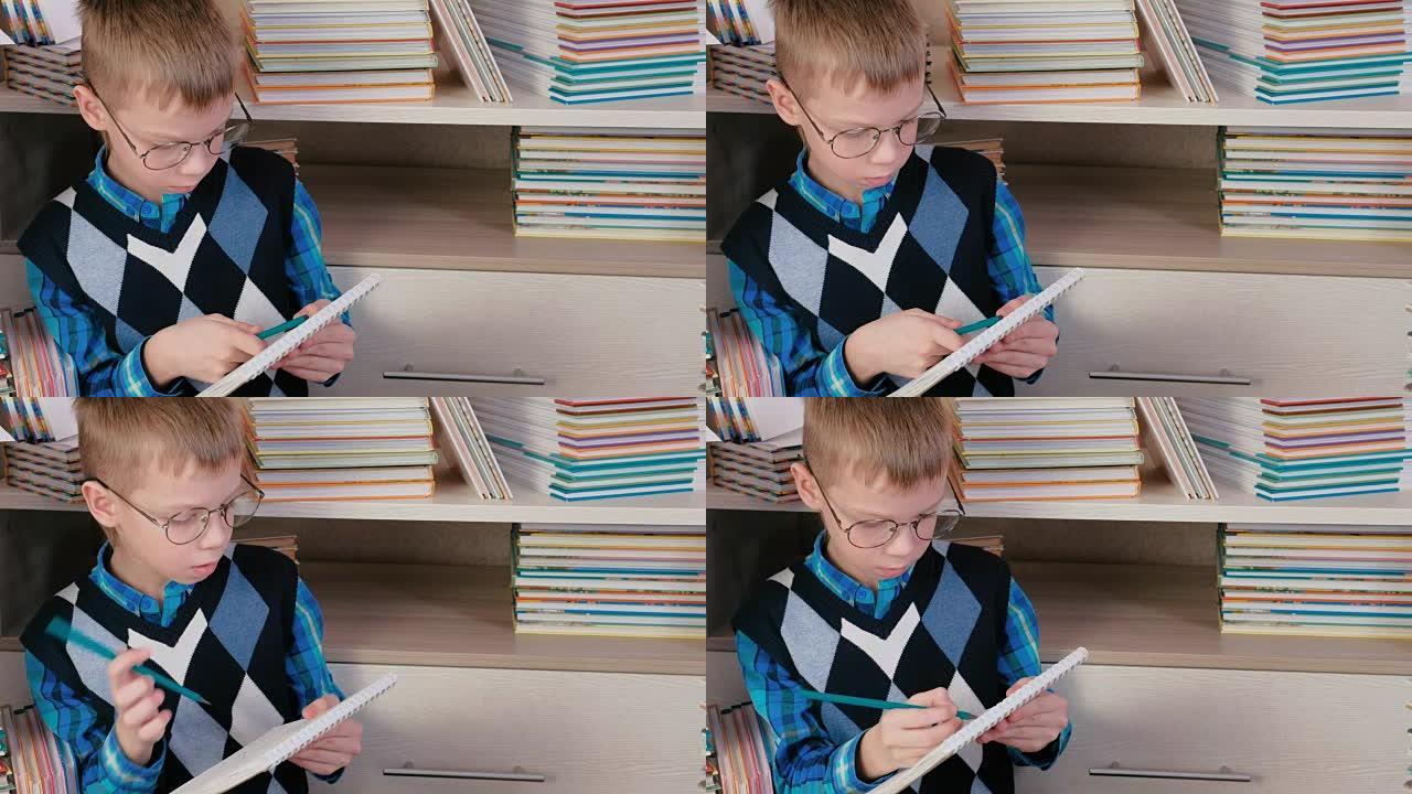 戴眼镜的七岁男孩在坐在书中的素描本上写东西。