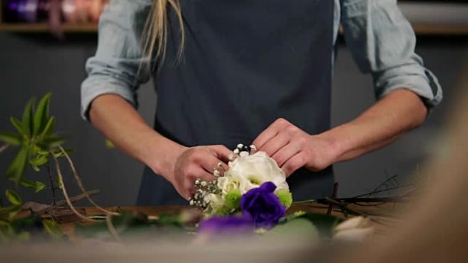一个花店助理的手的特写视图，用丝带绑在她桌子上的一束鲜花。慢动作镜头