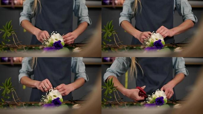 一个花店助理的手的特写视图，用丝带绑在她桌子上的一束鲜花。慢动作镜头