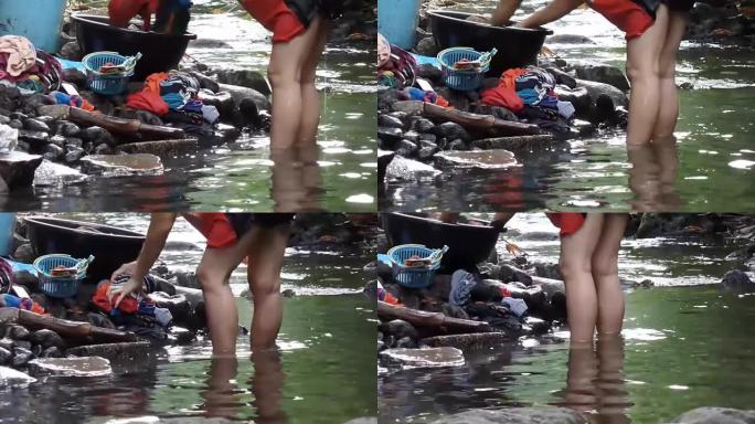 菲律宾农村社区缺乏公共供水系统设施，迫使这名妇女甚至在受污染的河流中洗衣服。跟踪镜头
