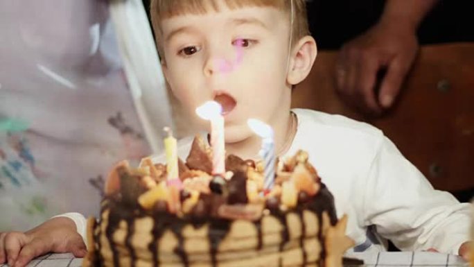 三岁的小男孩在生日蛋糕上吹蜡烛