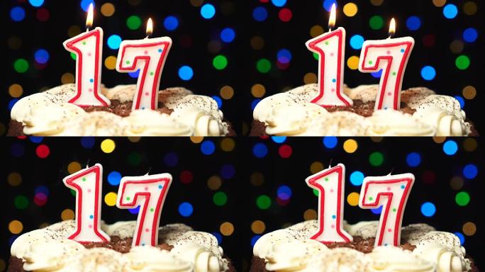 蛋糕上的第17号-十七岁生日蜡烛燃烧-最后吹灭。彩色模糊背景